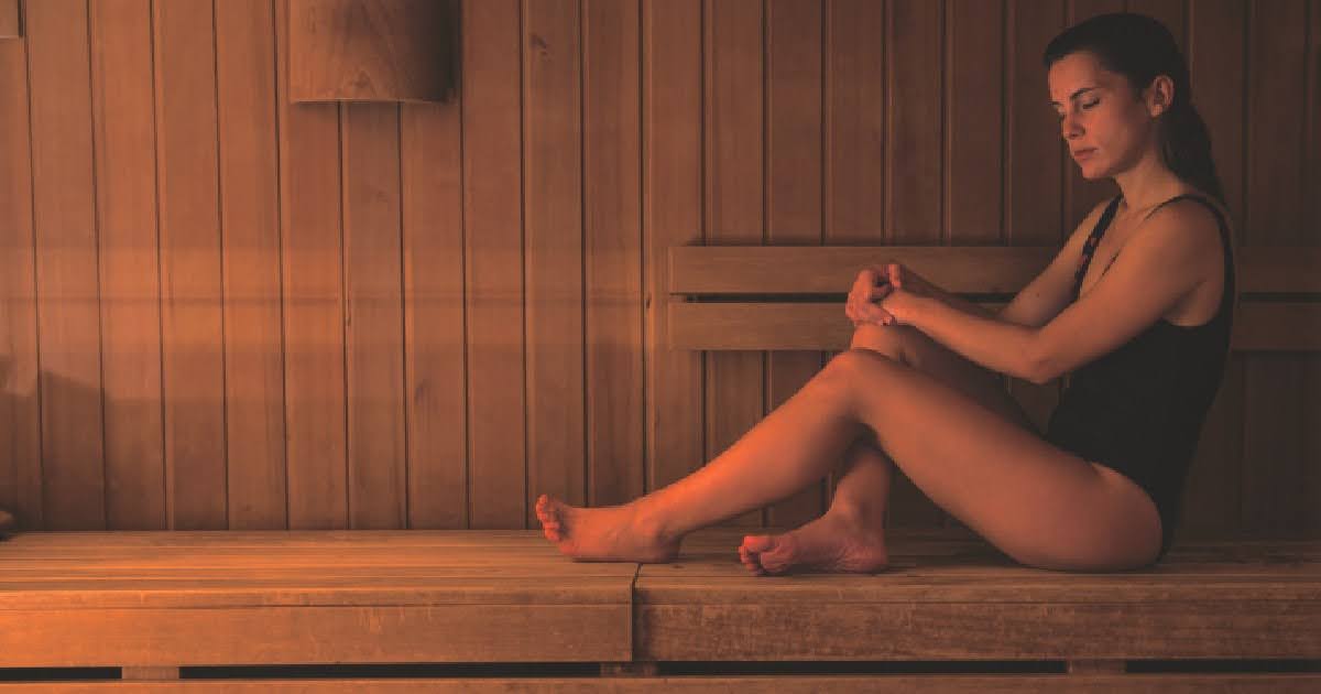 A woman relaxing in an infrared sauna, demonstrating one of the key benefits of infrared sauna use for better digestive health.