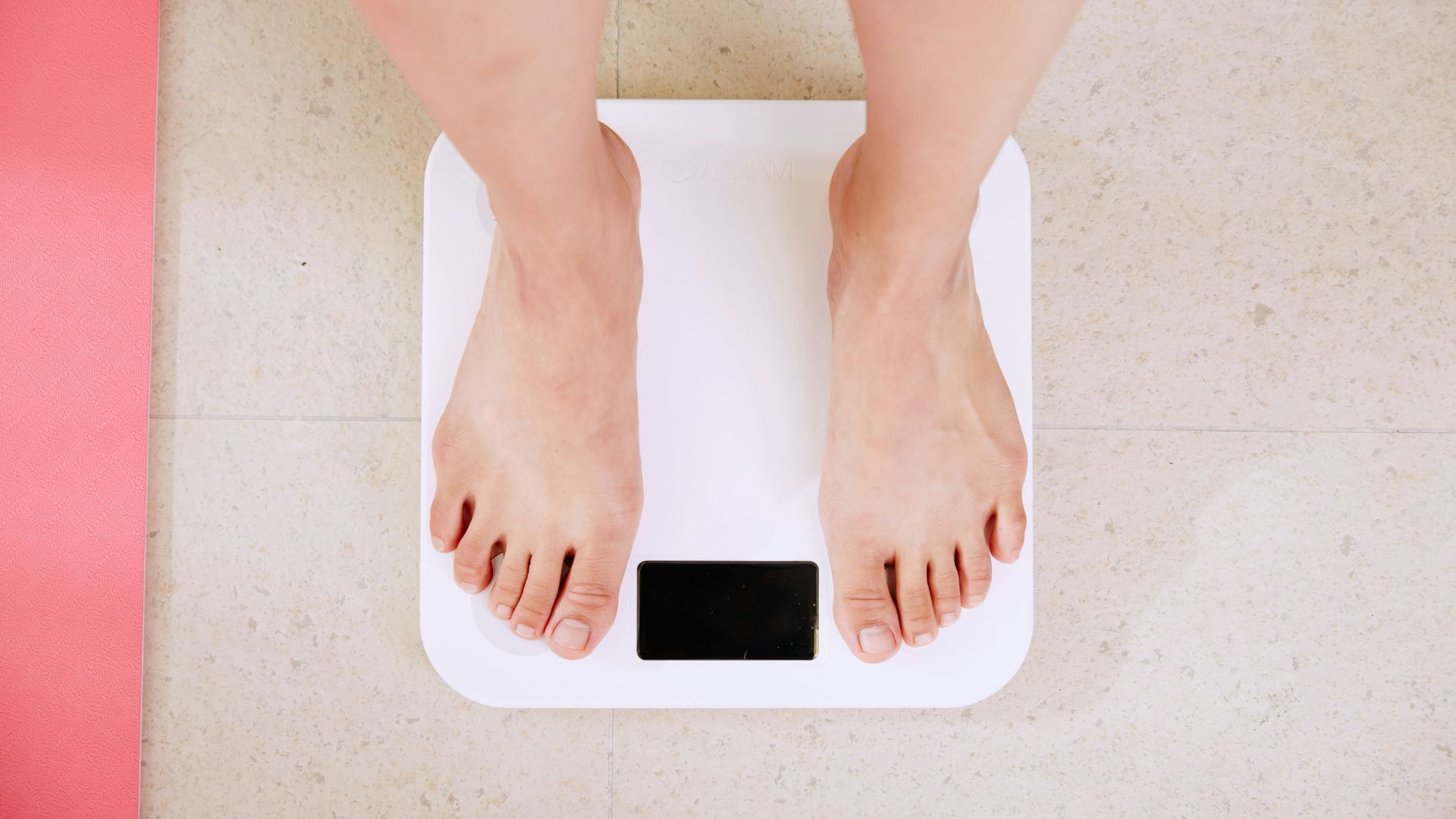 The feet of a woman standing on a scale, weight the effects of her infrared sauna for water retention