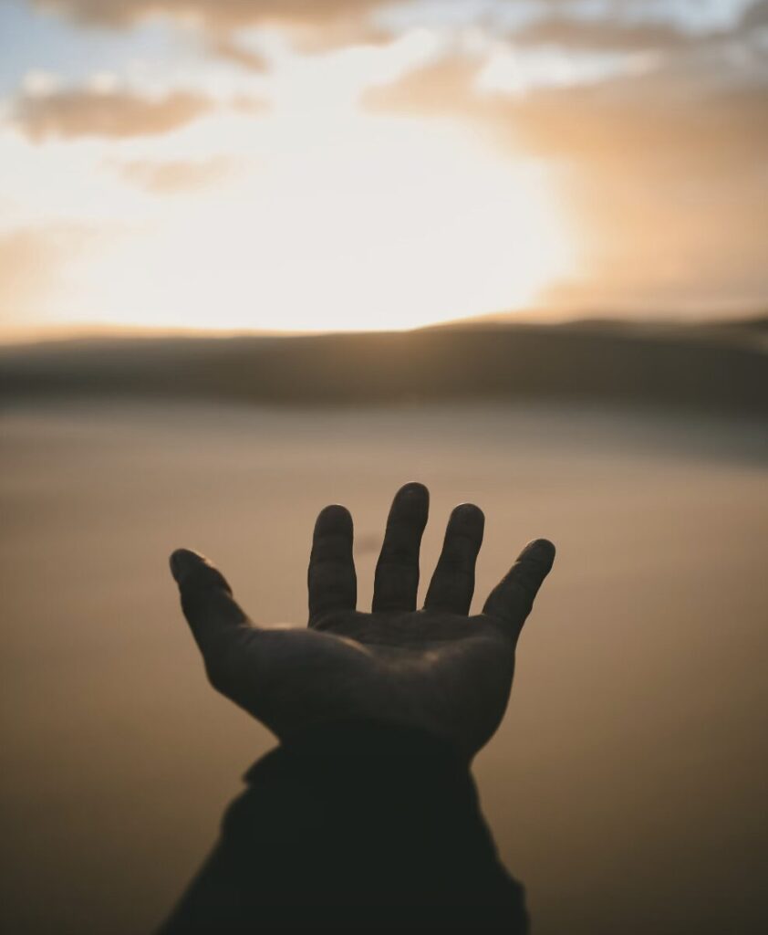 Hand outstretched toward sunset, infrared saunas for mental health