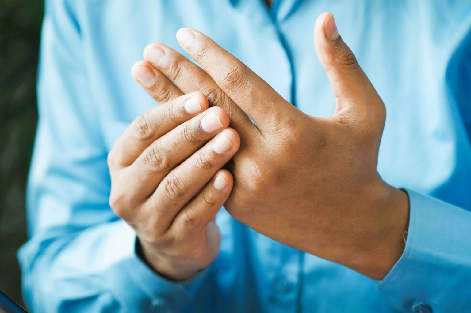 man clutches hand with nerve pain, in need of infrared sauna session